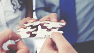 Group of business people holding a jigsaw puzzle pieces. Business solution integration concept. Multi ethnic group. Close up of hands